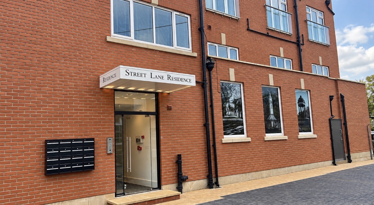 Communal entrance of the converted red-brick residential building with its canopy, signage and post boxes